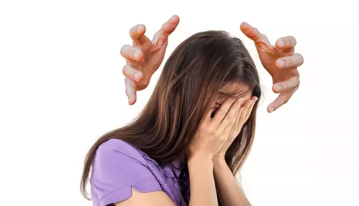 Chica con las manos en la cara y dos otras manos flotando alrededor de su cabeza.