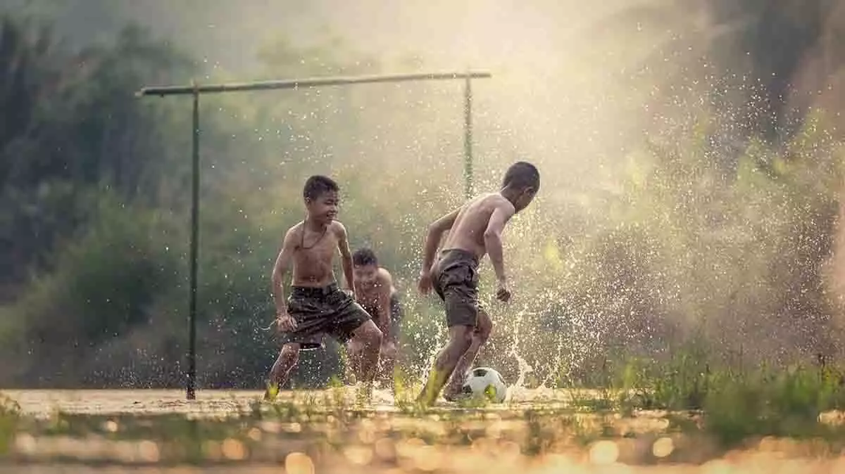 Niños descalzos jugando a fútbol.