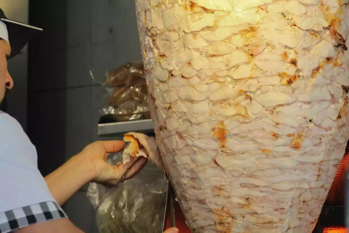 Un hombre trabajando con la carne de Kebab