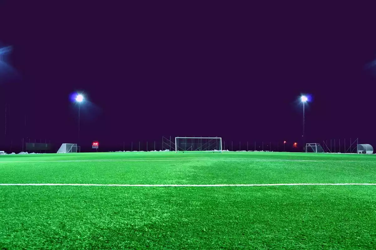 Campo de futbol plano general con cielo oscuro nocturno