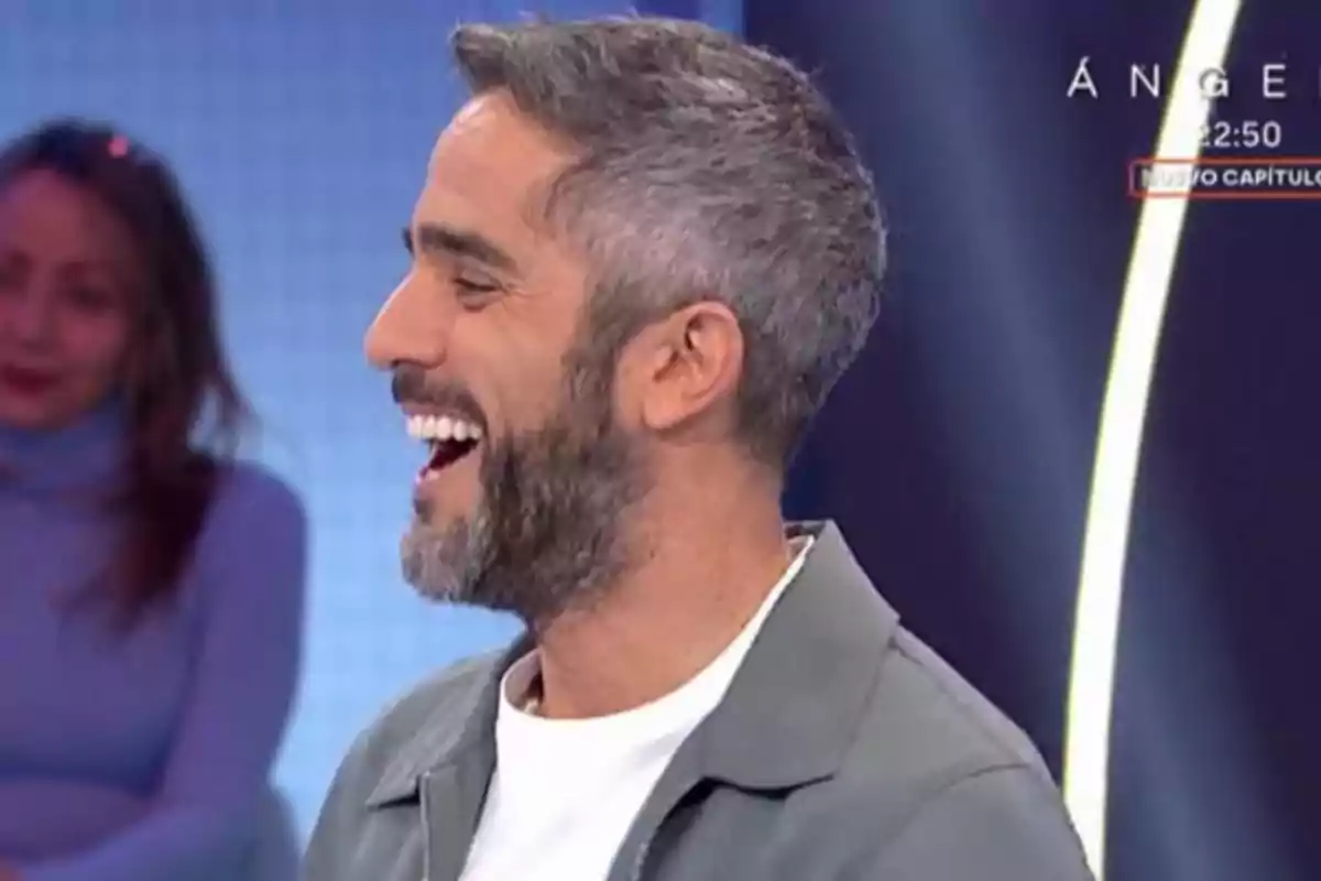 Roberto Leal con barba y cabello canoso sonríe ampliamente en un estudio de televisión. Roberto Leal con barba y cabello canoso sonríe ampliamente en un estudio de televisión.
