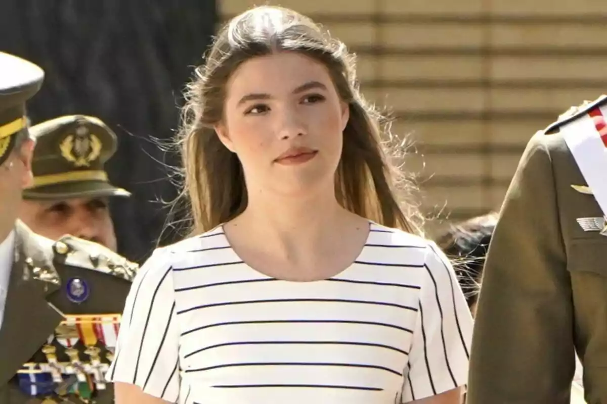 Infanta Sofia in a black and white striped shirt, surrounded by people in military uniforms.